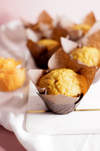 Vertical photo showing a Nick&Fritz Vegan Spiced Carrot  muffin on a marble board